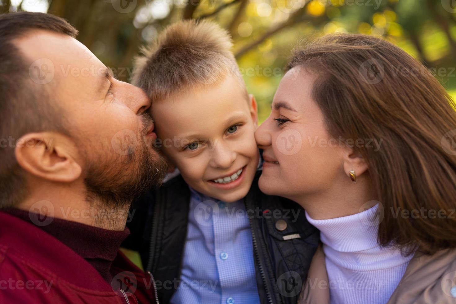 mamá y papá besando a un niño entre ellos, retrato de primer plano foto