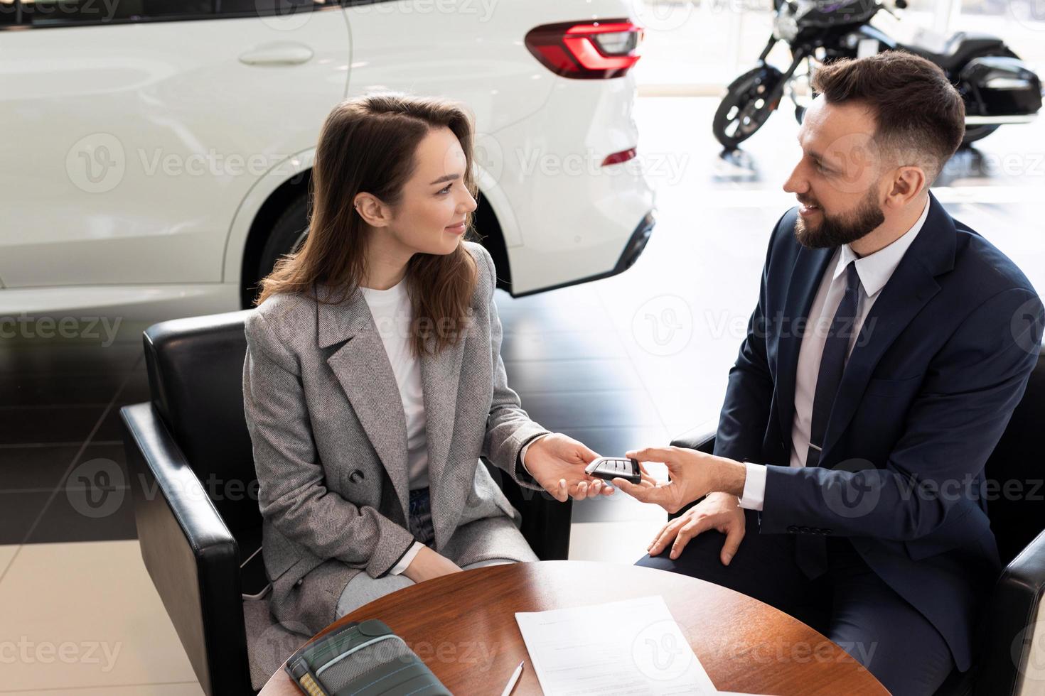 car dealership manager handing over keys to new car buyer. the concept