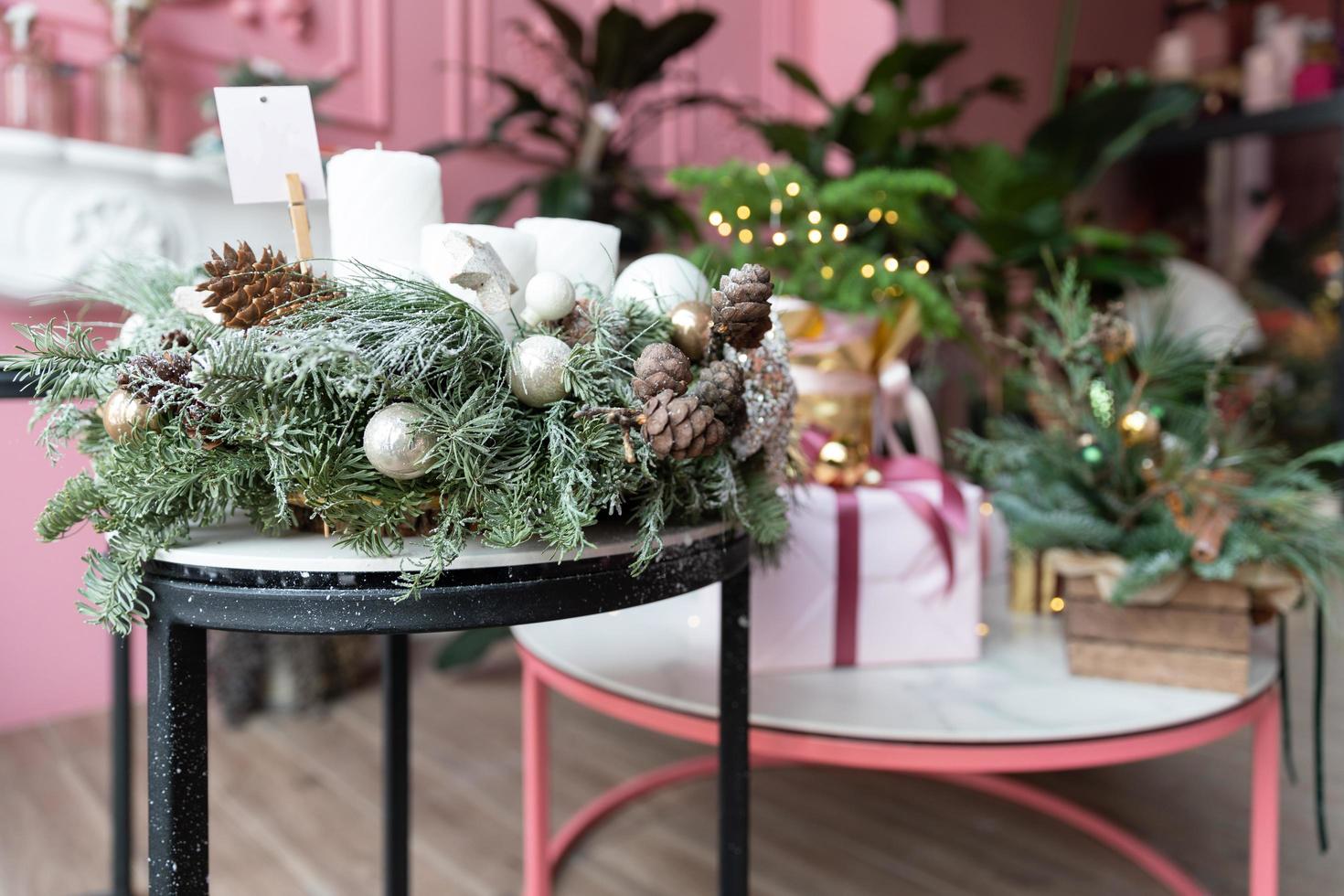 composición navideña de abeto natural con adornos de árboles de navidad y regalos para navidad en una mesa en un elegante interior rosa foto