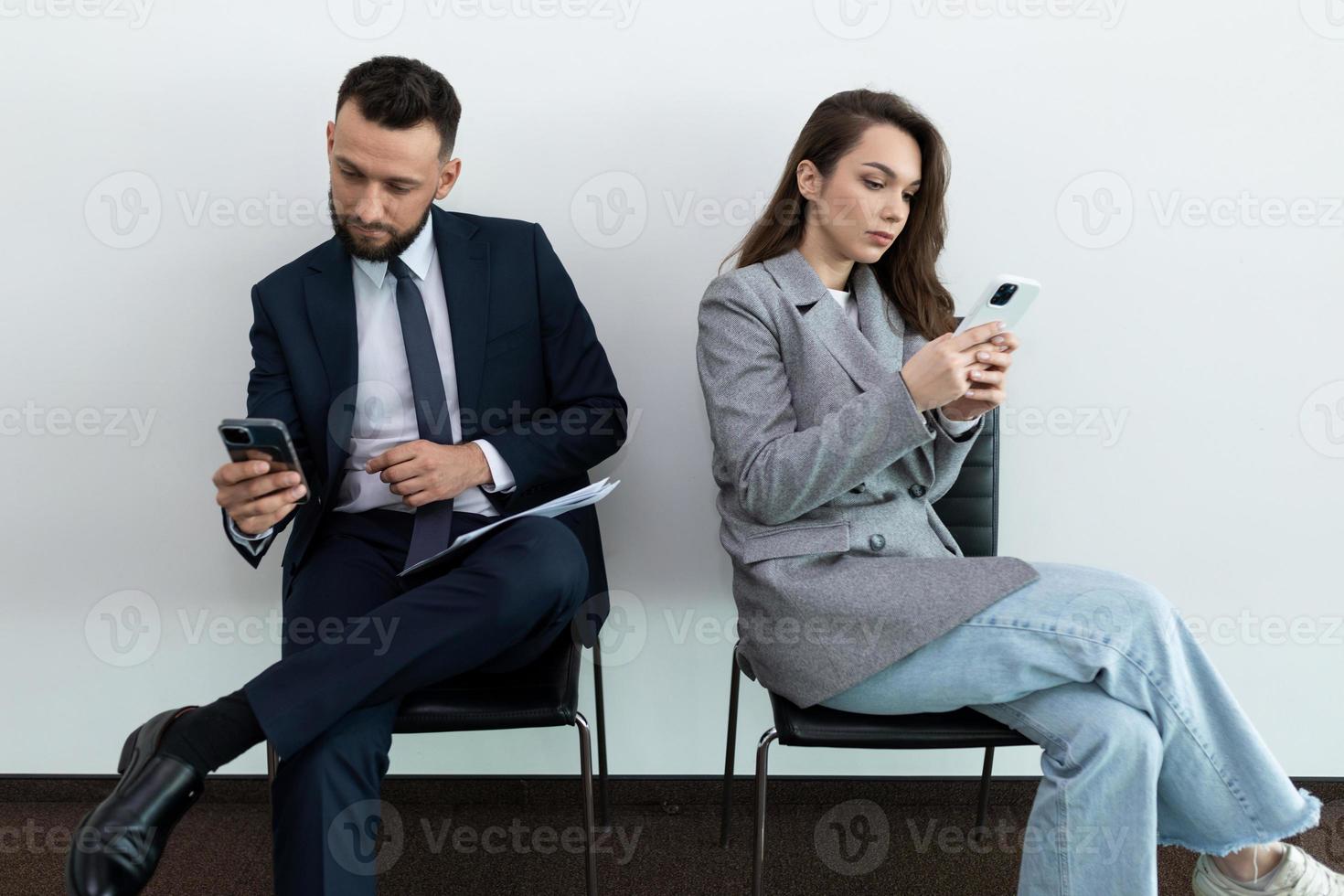 job seekers looking at their phones while waiting for an interview photo