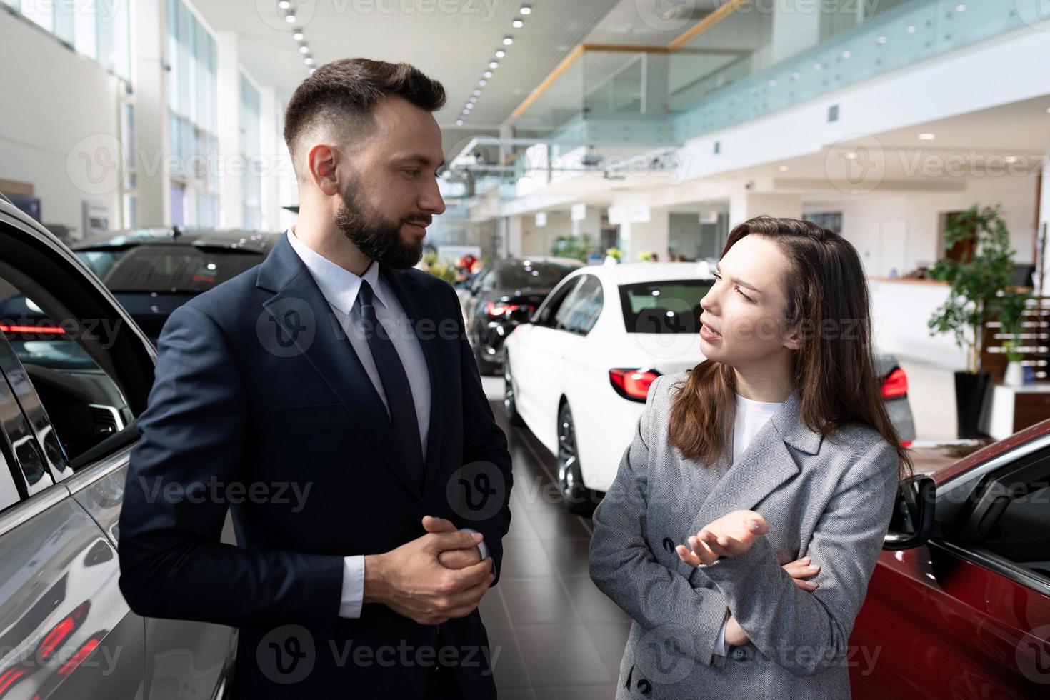 a young woman in a car dealership is interested in the terms of a loan to buy a new car photo