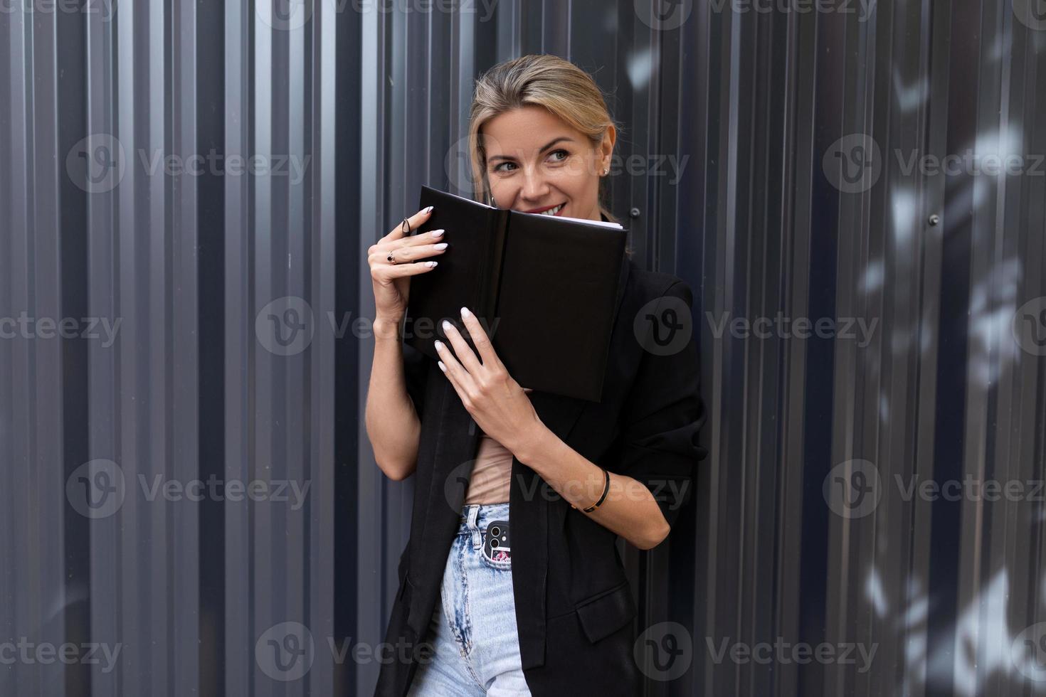 office worker middle-aged woman with a smile holding a notebook in her hands looking at the camera photo