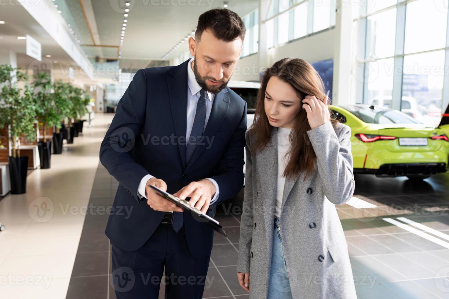 un empleado de un concesionario de automóviles ayuda a clasificar a una mujer compradora de seguros de automóviles, concepto de seguro de automóviles foto