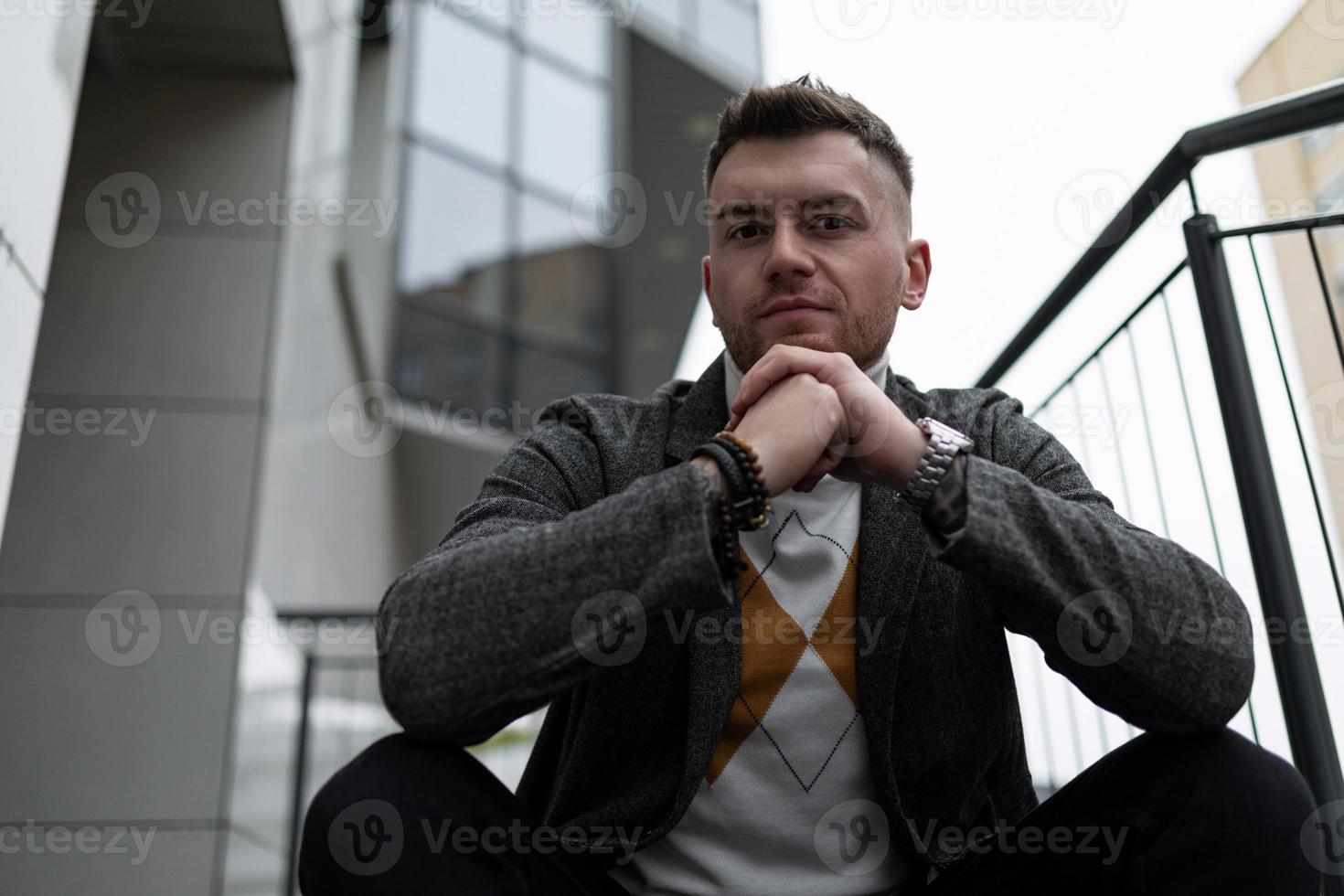 brutal portrait of a man sitting on the stairs with his hands folded in the lock photo