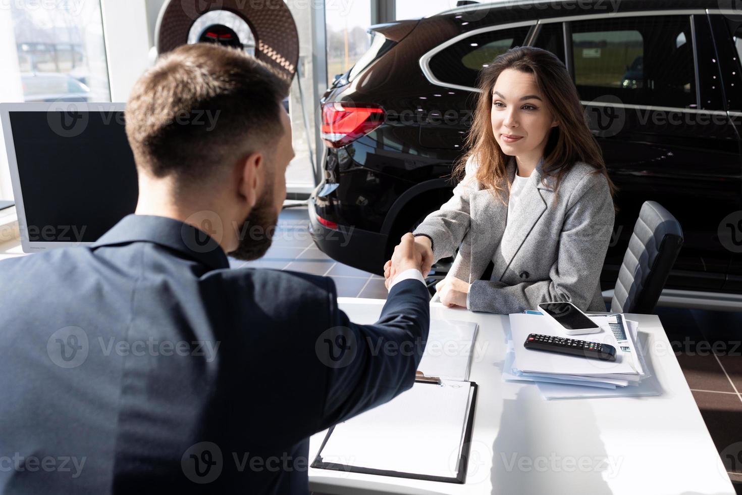 finalización de un trato en un concesionario de automóviles para la venta de un automóvil nuevo de una joven, concepto de alquiler de automóviles foto