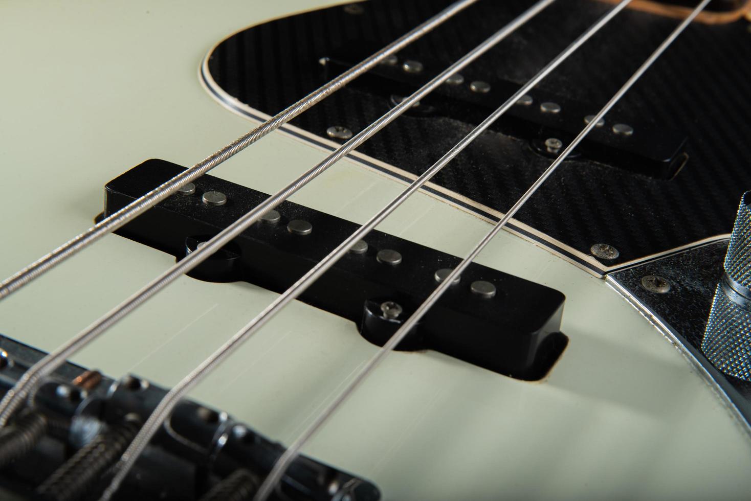 cierre los detalles de las cuerdas del bajo de la guitarra, cuatro cuerdas de hierro, color blanco y negro foto