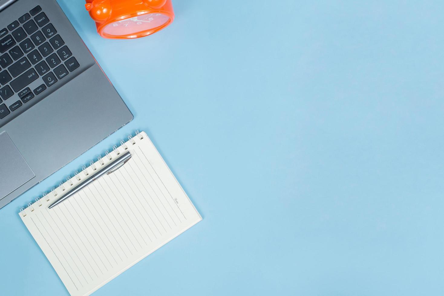 Top view of Office Table top with laptop computer, orange clock and notebook with space photo