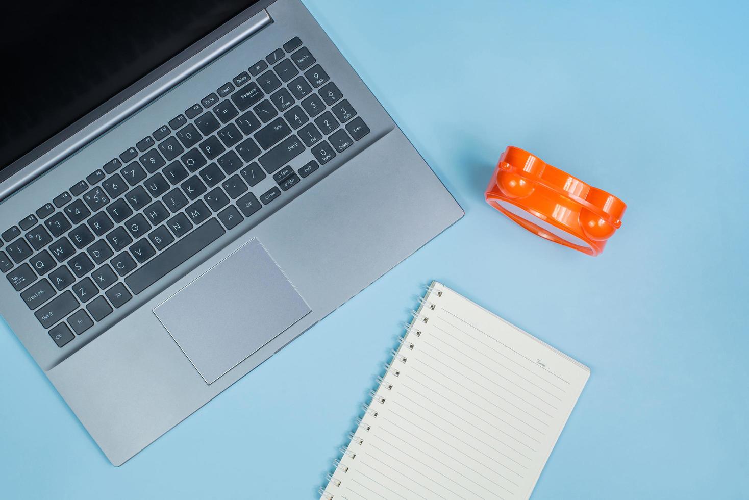 Top view of Office Table top with laptop computer, orange clock and notebook photo