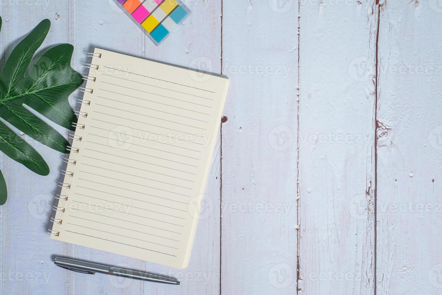 Top view image of notebook with pen and xanadu leaf on wooden table photo