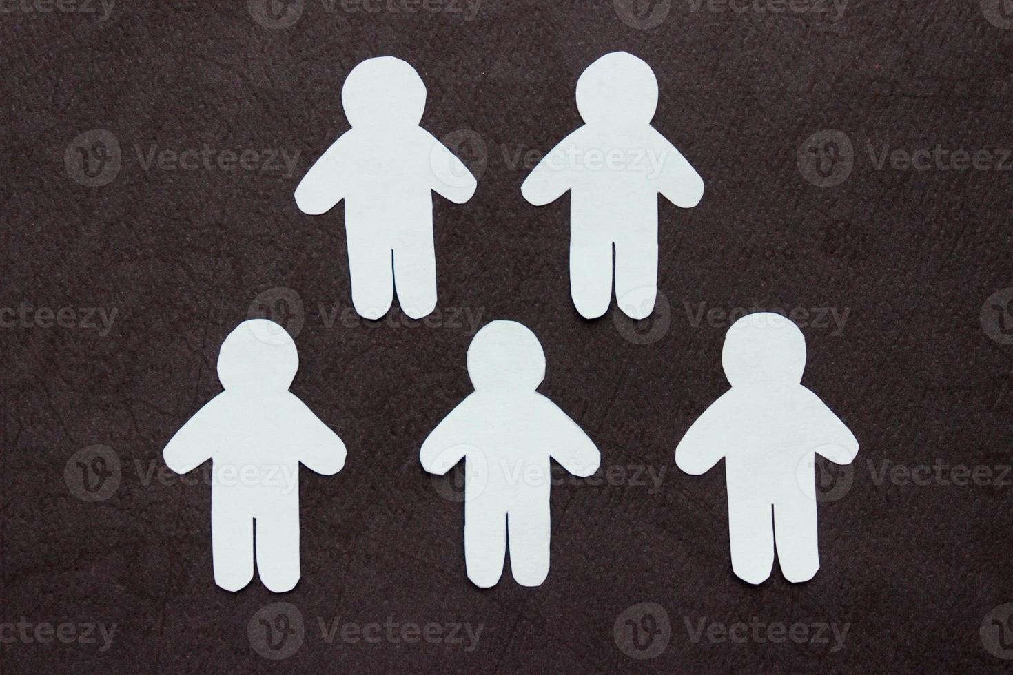 Silhouettes of five people cut from white paper. On black background. Group of people. Teamwork, communication, togetherness, friendship photo