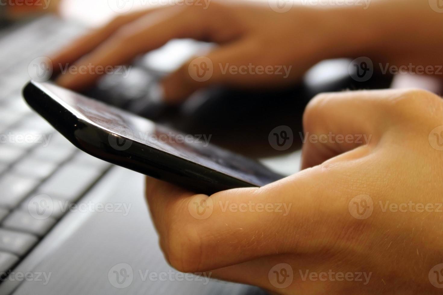 The girl sits at a laptop and holds a smartphone in her hands. Business concept. Online Shopping. Blurred background. photo