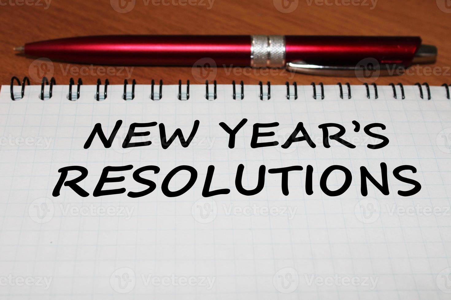 Notepad with a pen on a wooden table. View from above. The concept of resolutions for the new year. photo