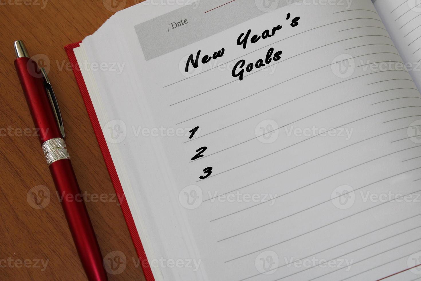 Notepad with a pen on a wooden table. View from above. The concept of goals for the new year. photo