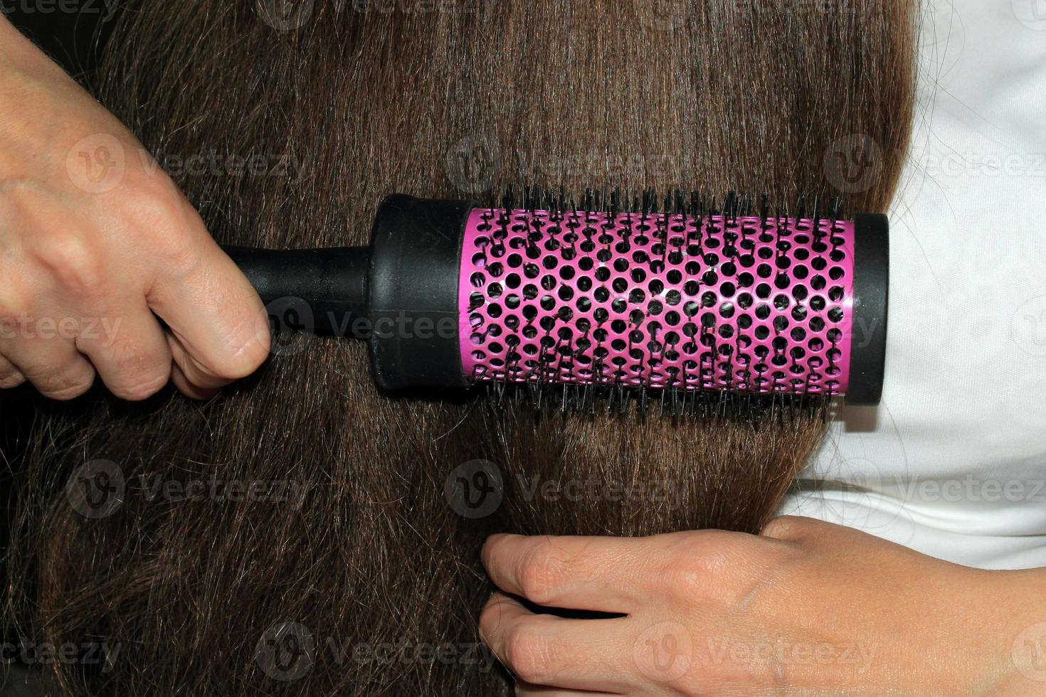 A girl with dark long hair combs her hair. Hair care. Hair loss problem. photo