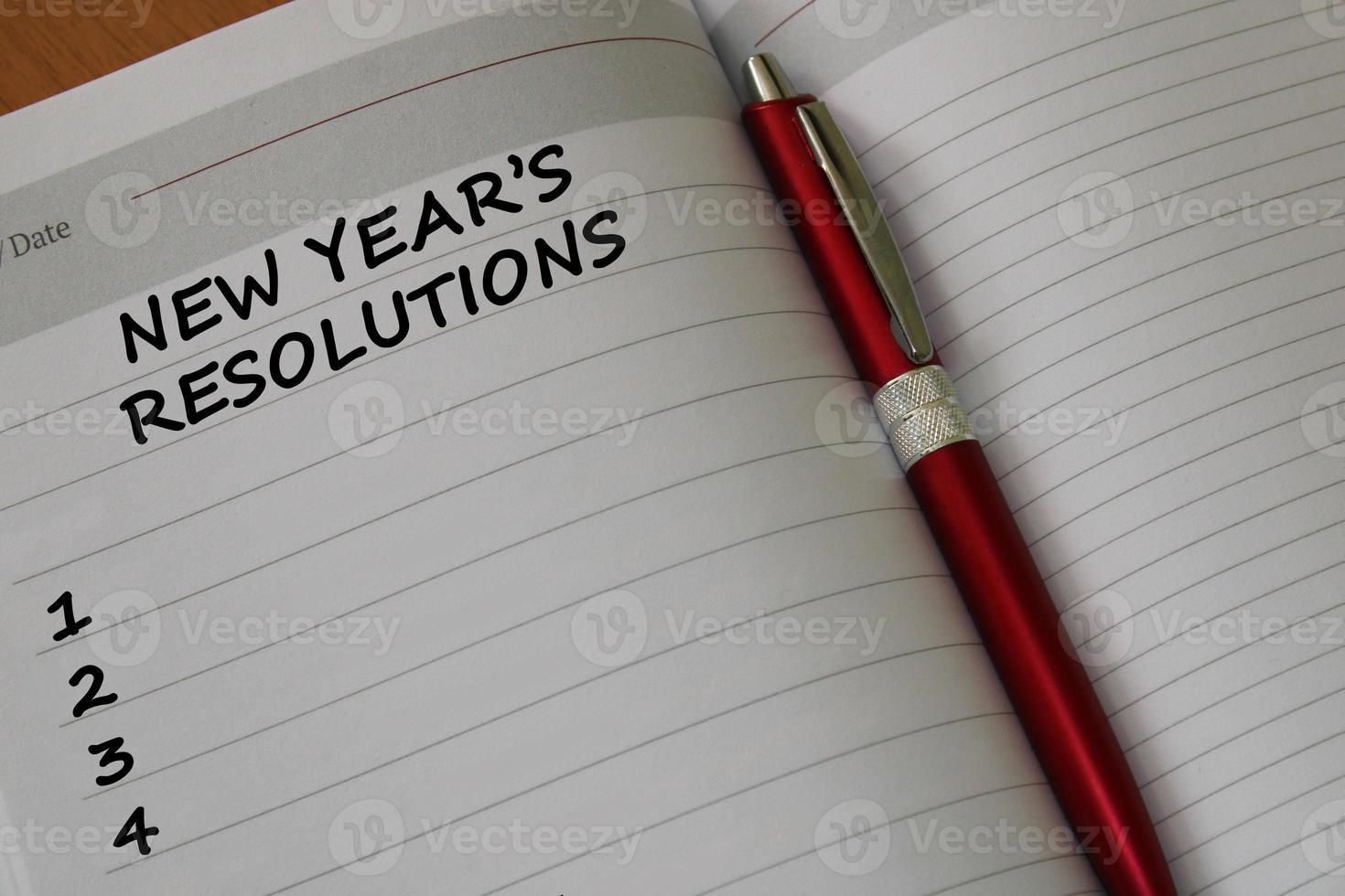 Notepad with a pen on a wooden table. View from above. The concept of resolutions for the new year. photo