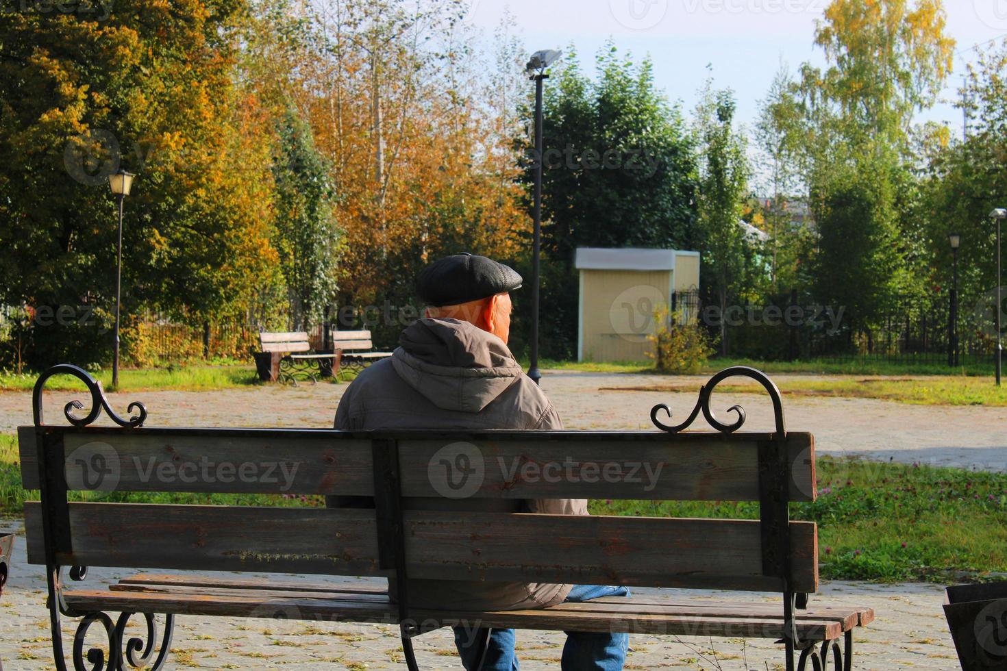 un anciano se sienta en un banco en un parque de la ciudad. foto