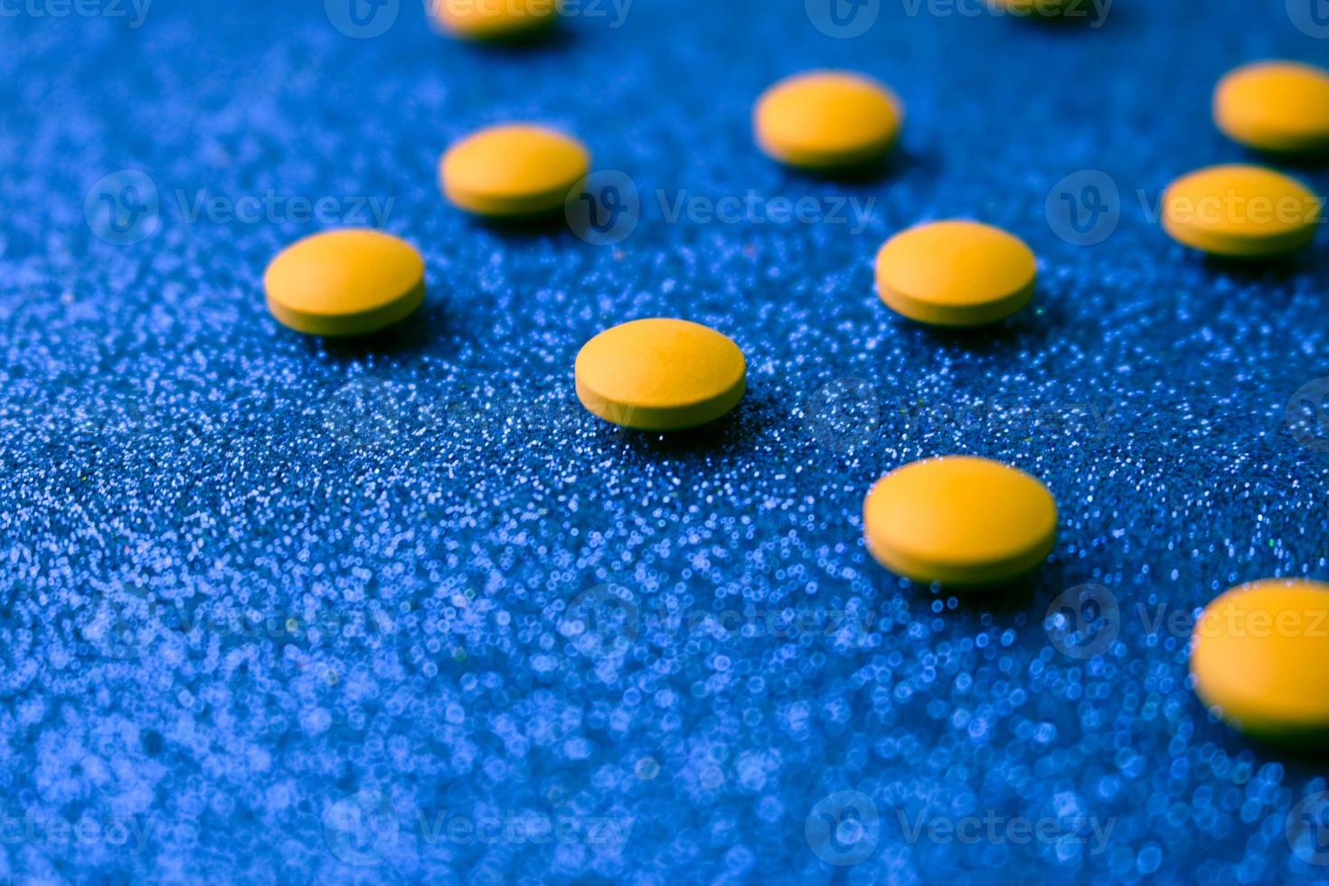 Small yellow orange beautiful medical pharmaceptic round pills, vitamins, drugs, antibiotics on a blue background, texture. Concept medicine, health care. Flat lay, top view photo
