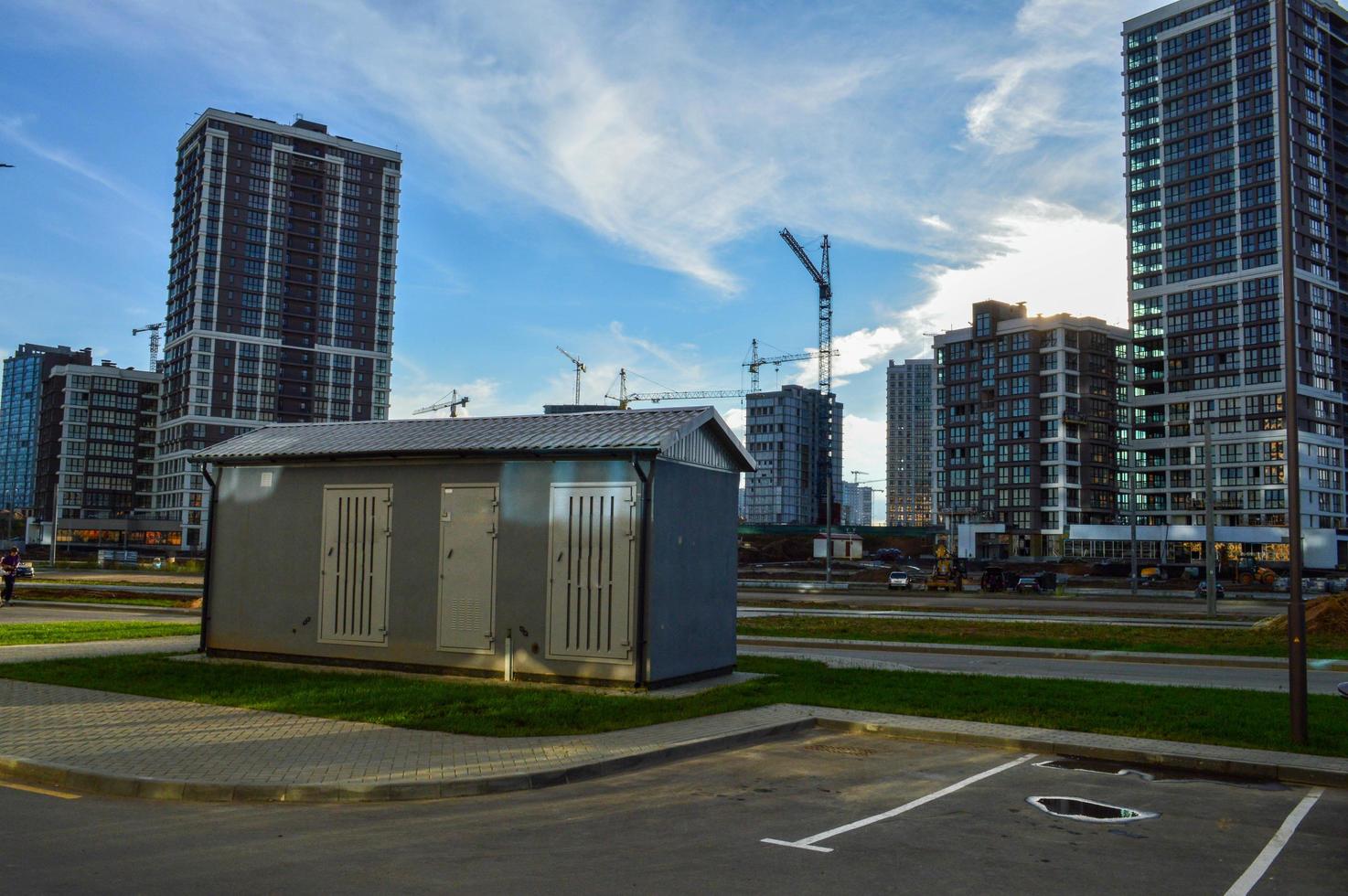 electrical house with power lines. concrete house with insulation and air conditioning for electricity shields. against the background of glass houses of a new residential complex photo