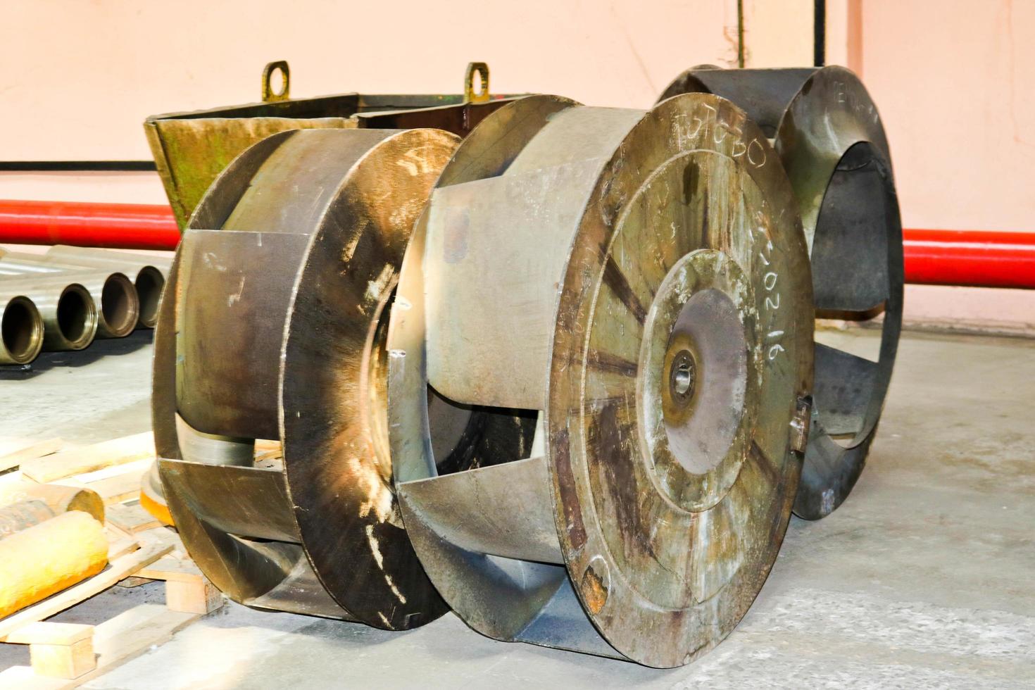 A large iron metal round wheel with louvers to pump water into the pump. Spare part of the transfer pump photo