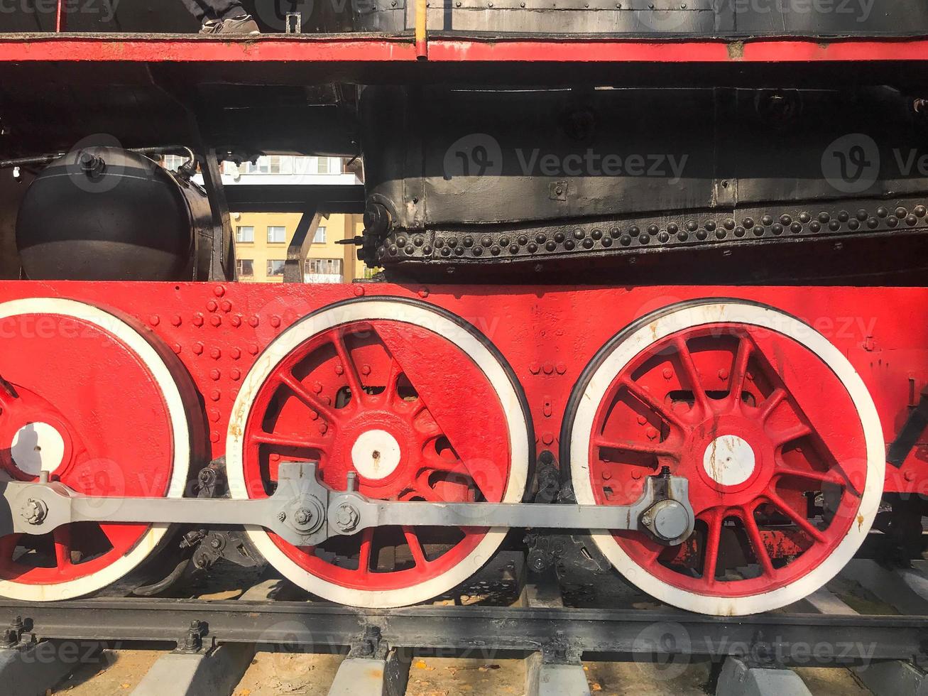 Large iron wheels of a red and black train standing on rails and suspension elements with springs of an old industrial steam locomotive photo