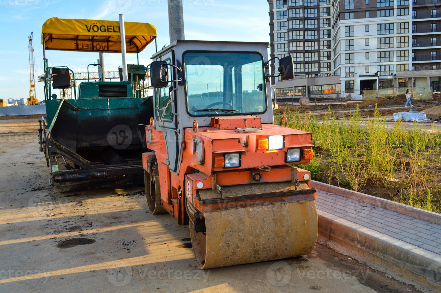 máquina para crear una superficie mejorada en la carretera junto al rodillo. dispositivos para la construcción de carreteras. paisaje urbano, creación de carreteras foto