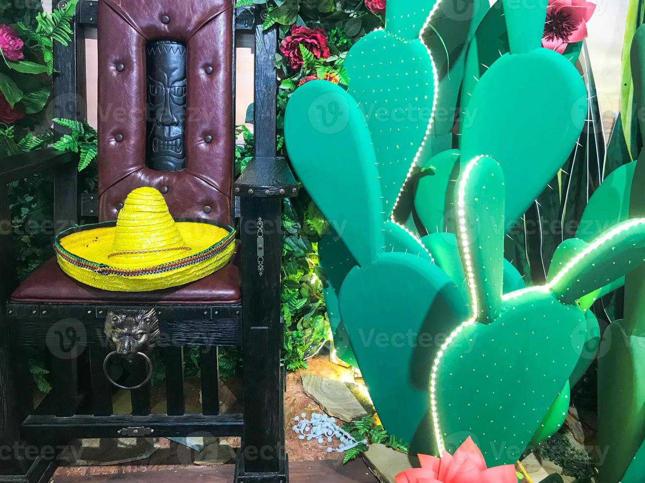Abstract plastic funny beautiful joyful Mexican cacti with flowers and a chair with a sambrero hat. The background photo