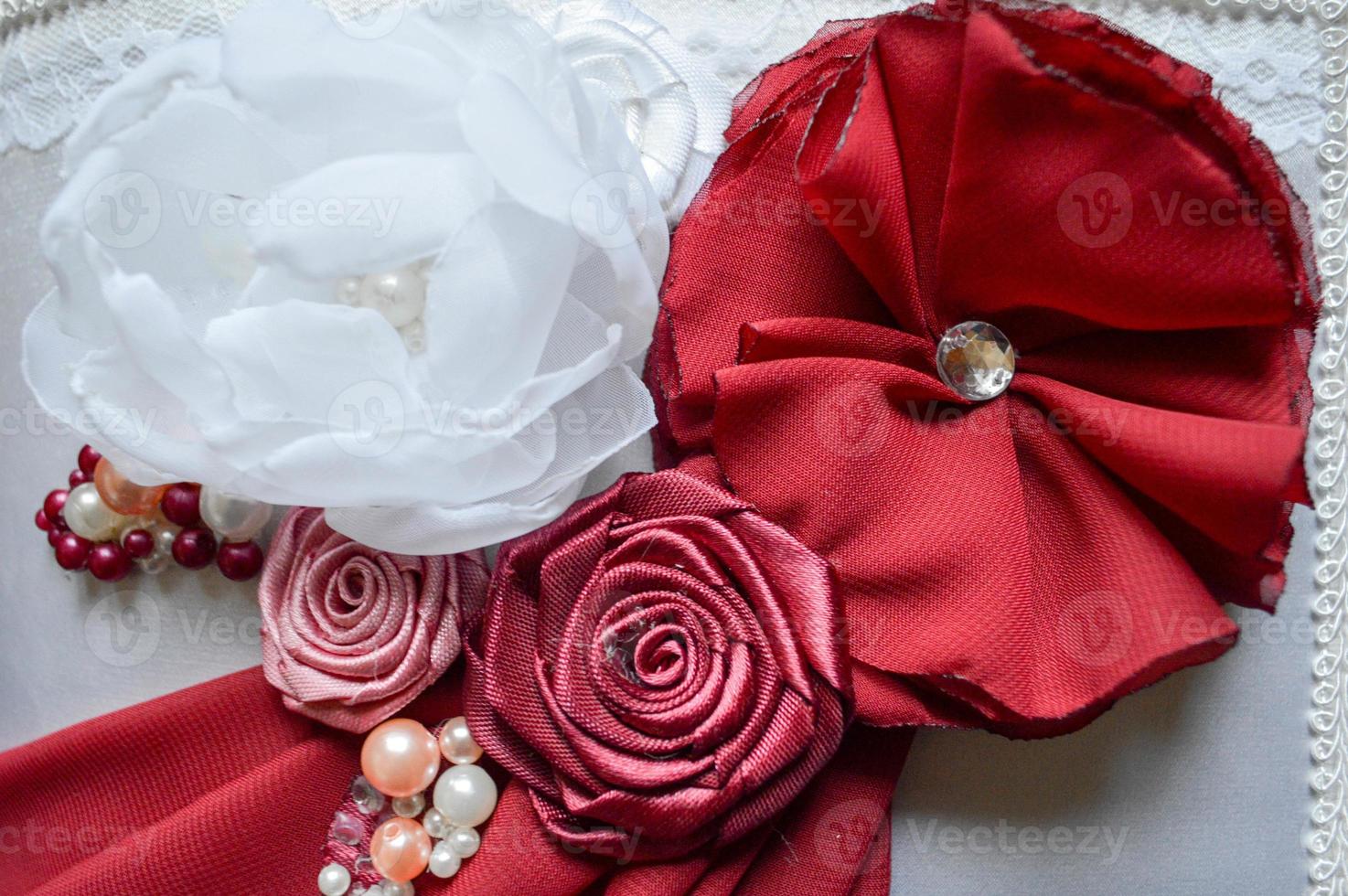 Red and white homemade flowers from a beautiful fabric decorated with rhinestones, pearls and beads. photo