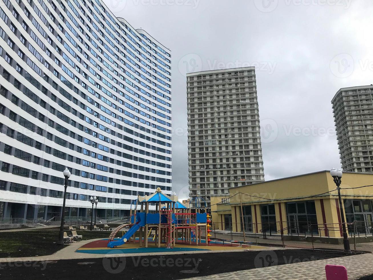 urban landscape, high-rise apartment buildings in blue and white. next to a house of unusual shape, like a wave. an urban reality in the city center with tall buildings and entertainment photo