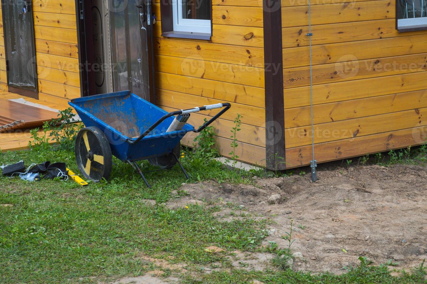 Construction industrial two-wheeled cart, wheelchair, tool stands on the street near the house of a garage at a construction site photo