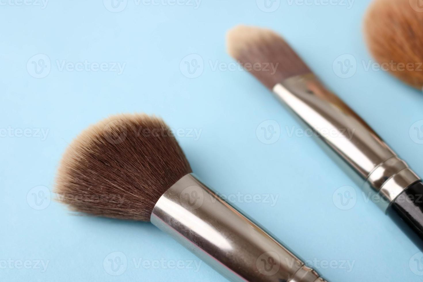 Beauty box, crumbly matte mineral powder with a special brown beautiful wooden brushes from natural nap for makeup on a warm blue background. Flat lay. Top view photo