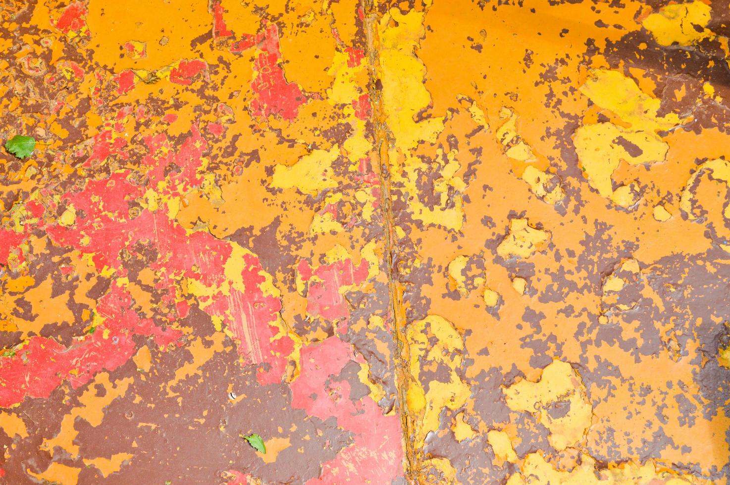 Texture of iron metal painted multicolored red yellow peeling paint of old battered scratched cracked ancient rusty metal sheet wall with corrosion. The background photo