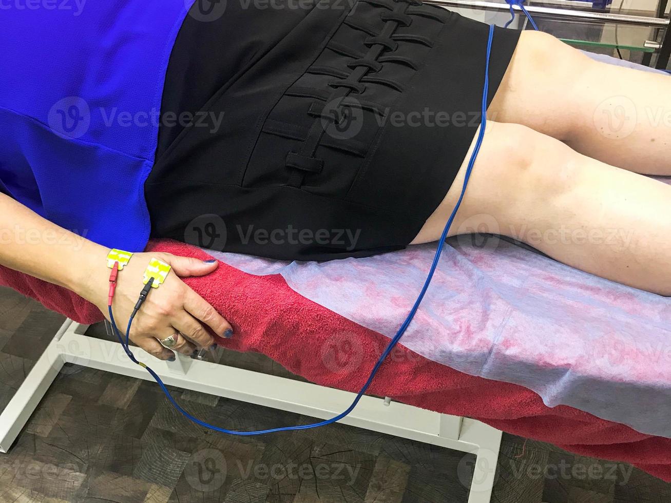 A person is given a bioimpedance medical analysis to diagnose body composition. Sensors are connected to the arm for medical analysis and patient care photo