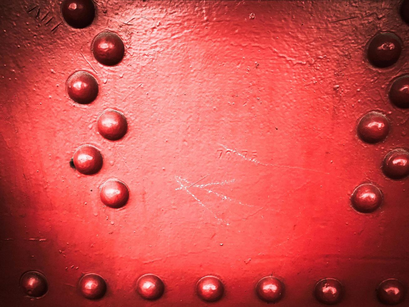 Red iron metal rough painted strong solid industrial wall with rivet holes and bolts. Background, texture photo