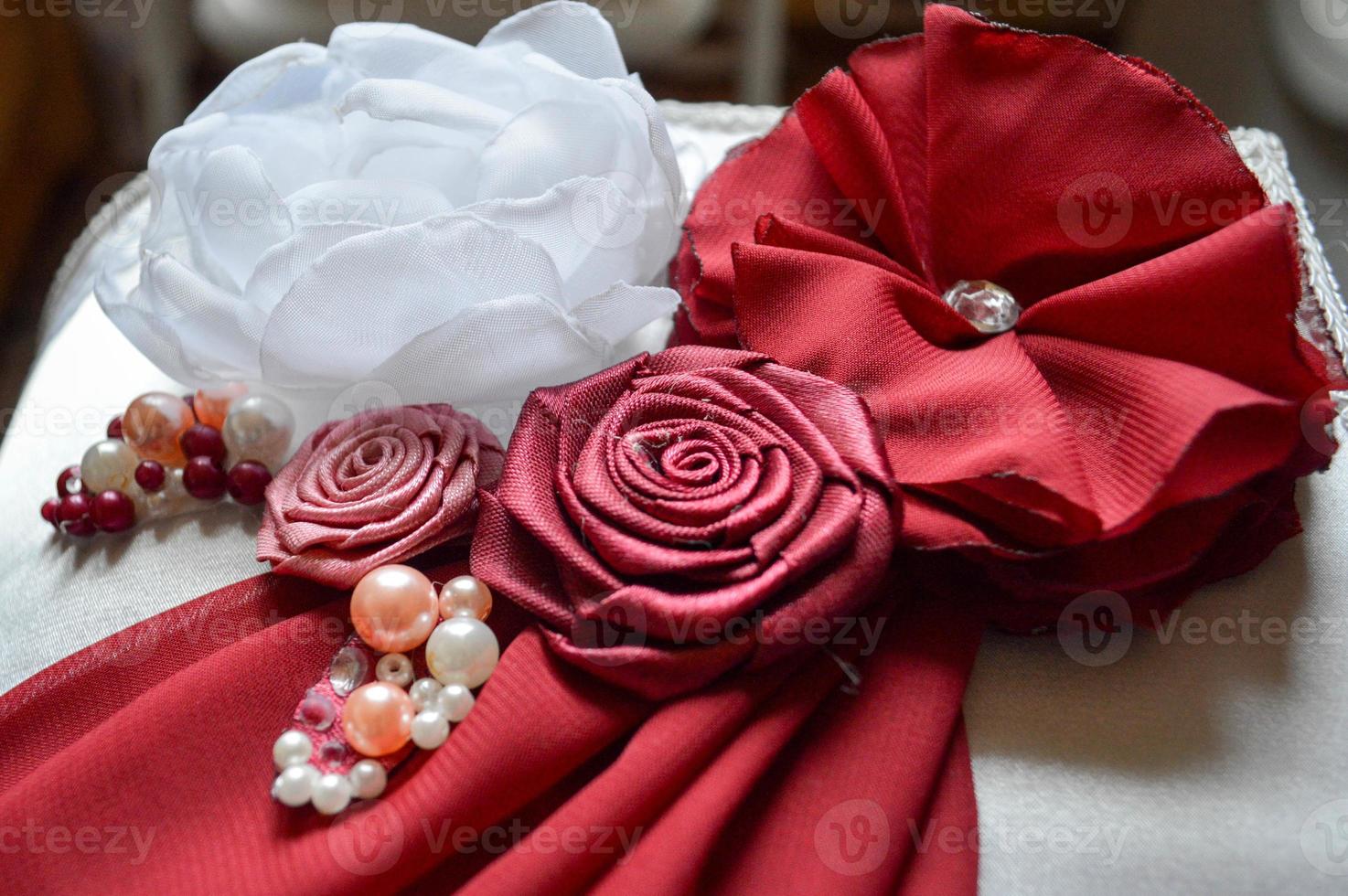 Red and white homemade flowers from a beautiful fabric decorated with rhinestones, pearls and beads. photo