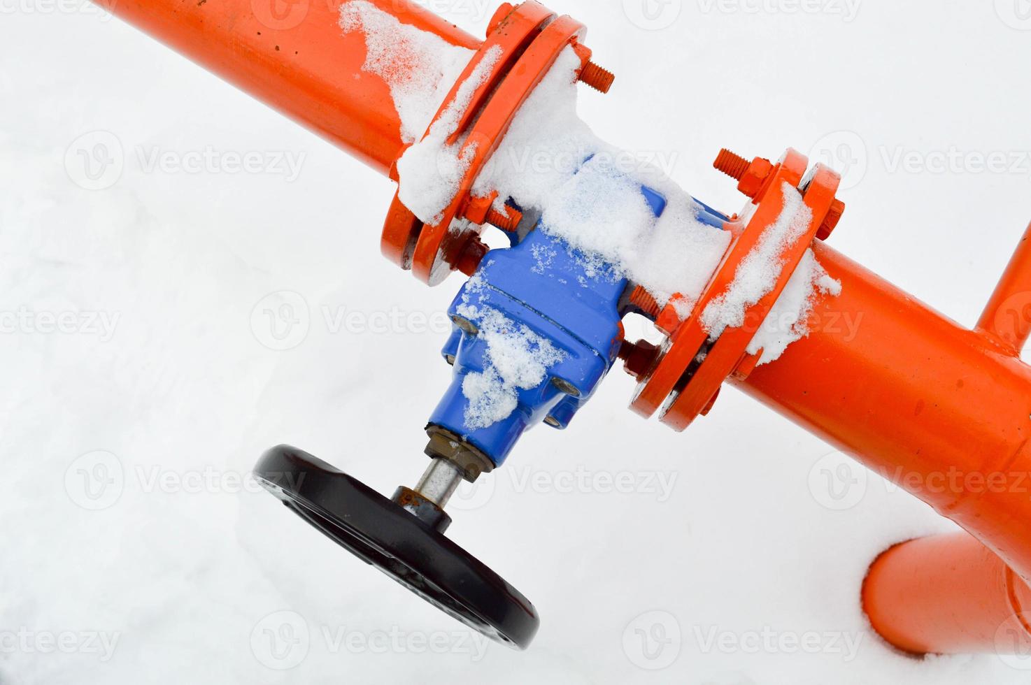 Industrial shut-off regulating protective pipe fittings. Black valve for opening, closing on an iron orange metal pipe with flanges, studs, nuts against the background of white snow in winter photo