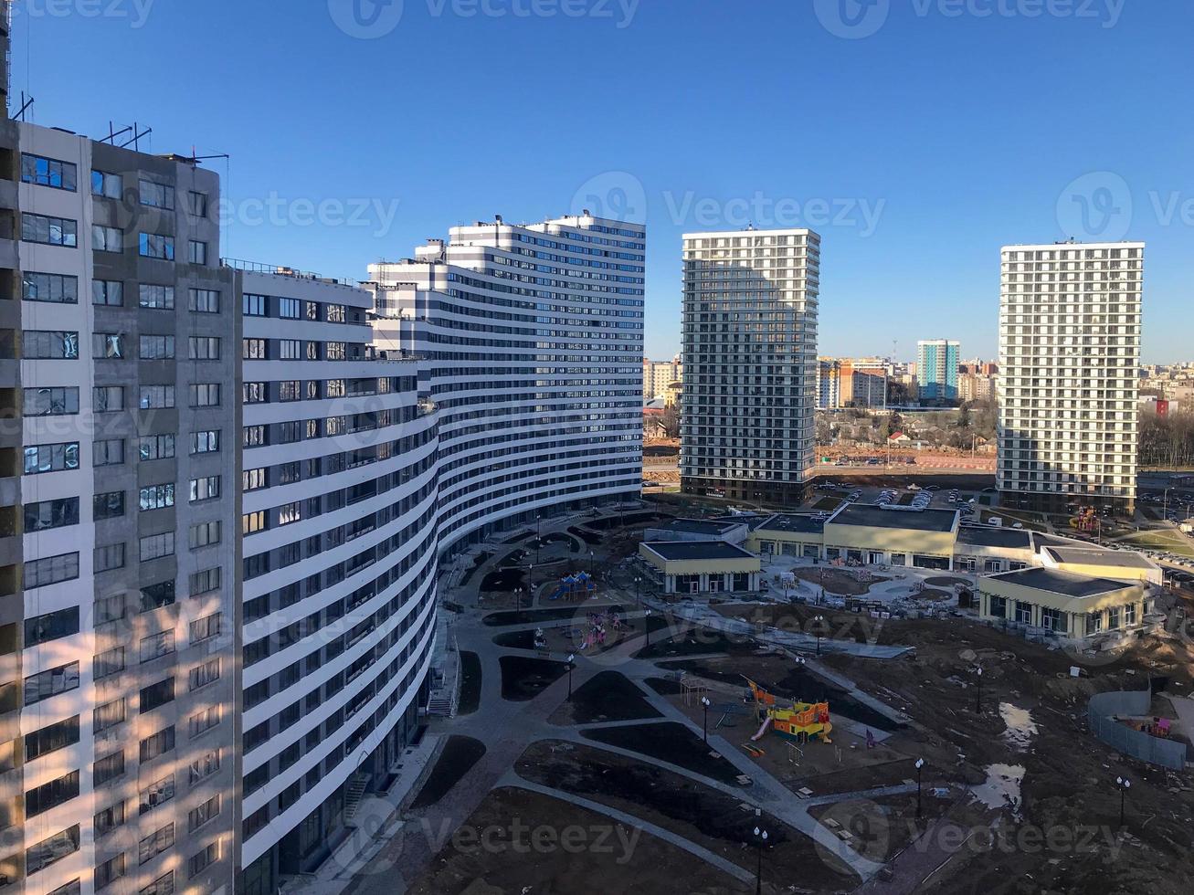 construction of a new area. view from above. construction of playgrounds. tall houses, white and blue curved unusual shapes. pillars of new buildings are on the lawn for playing with children and pet photo