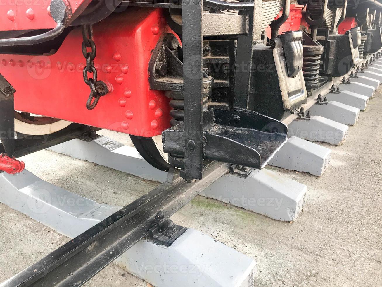 Large iron wheels of a red and black train standing on rails and suspension elements with springs of an old industrial steam locomotive photo
