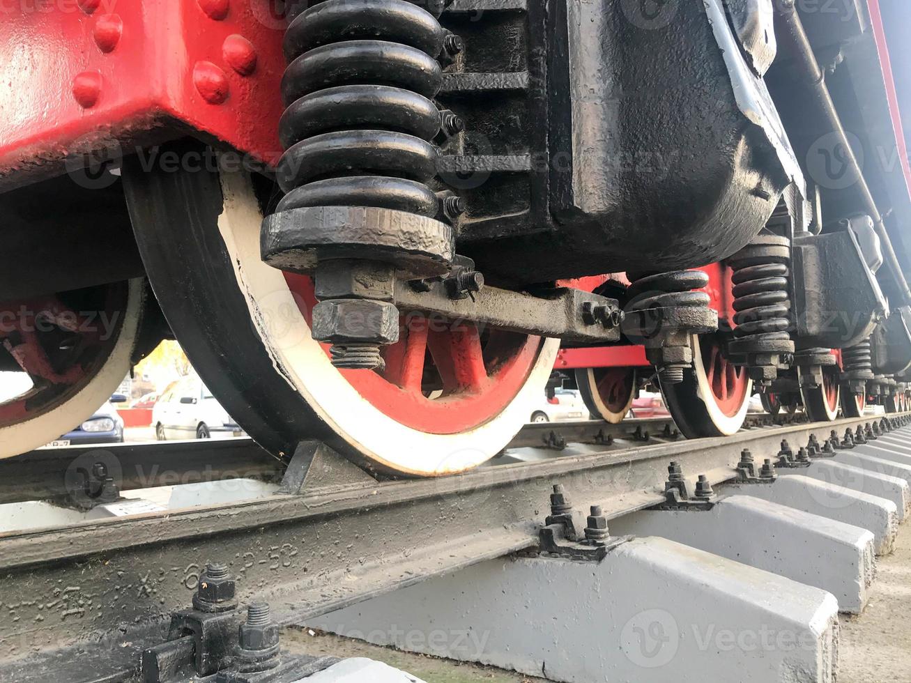 Large iron wheels of a red and black train standing on rails and suspension elements with springs of an old industrial steam locomotive photo