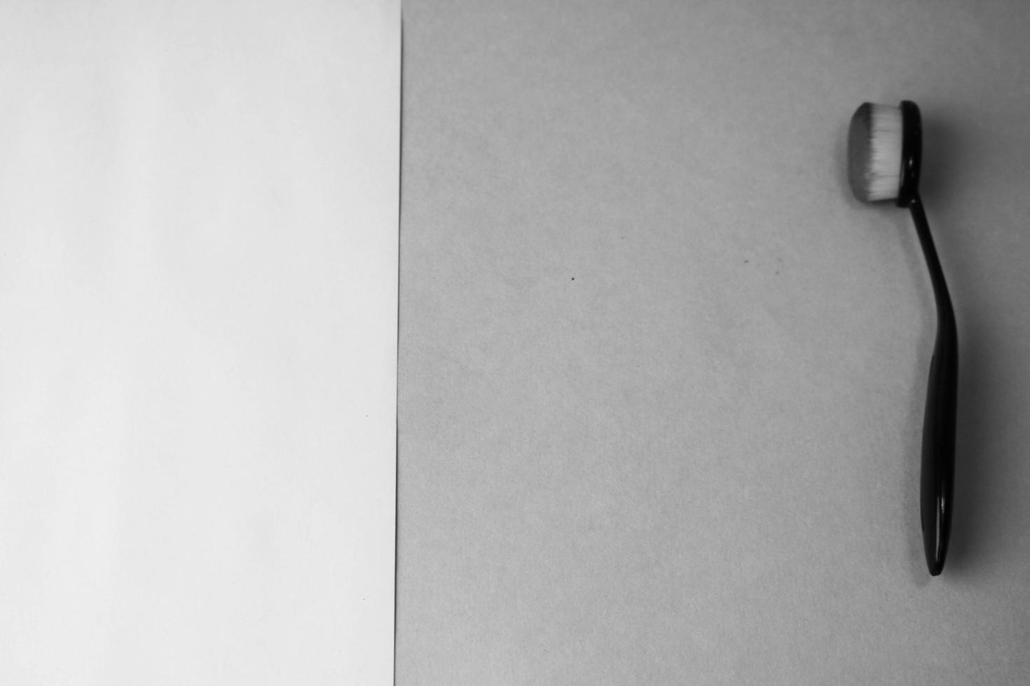 Wooden brush made of natural lint for applying tone on a black and white background. Flat lay. Top view photo