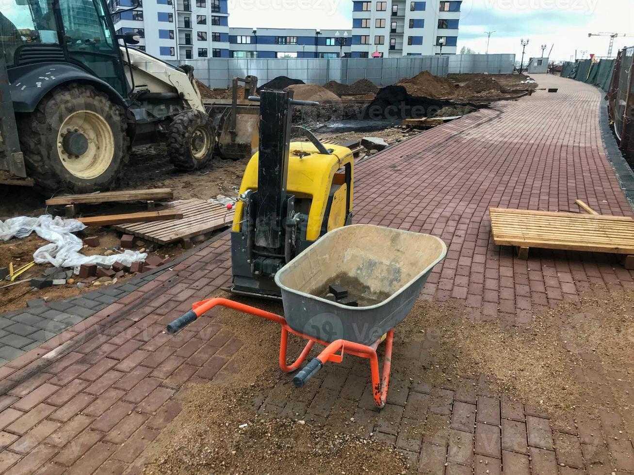 trolley for transporting heavy materials, concrete, bricks and sand. next to the machine for the manufacture of road surfaces. against the background of the wheels of a caterpillar tractor photo