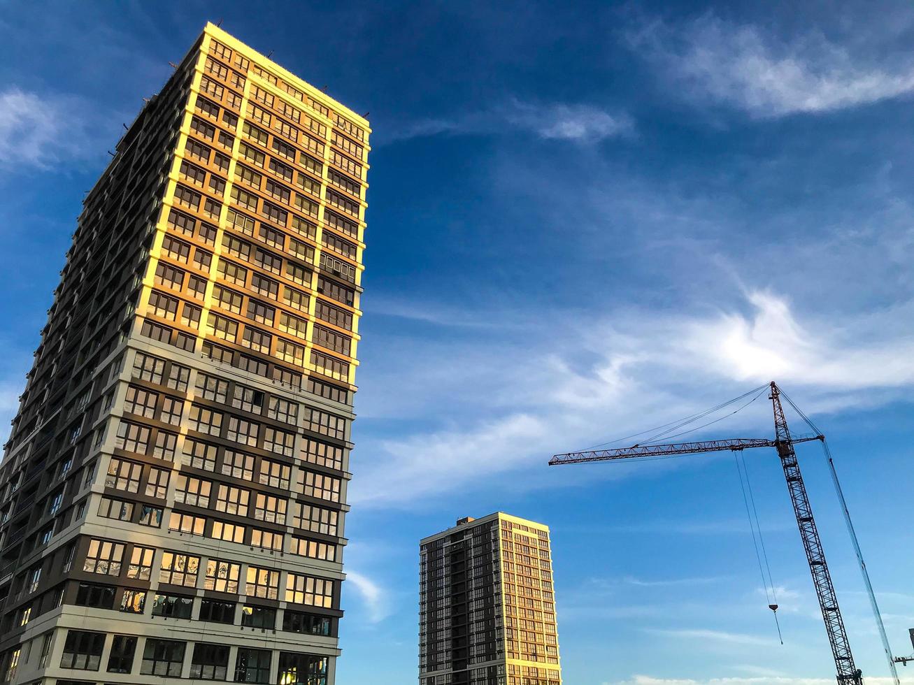 edificio de varios pisos marrón y blanco en el centro de la ciudad. hay un pequeño edificio al lado del edificio de gran altura. transición de casa en casa a lo largo del puente. contra el cielo azul foto