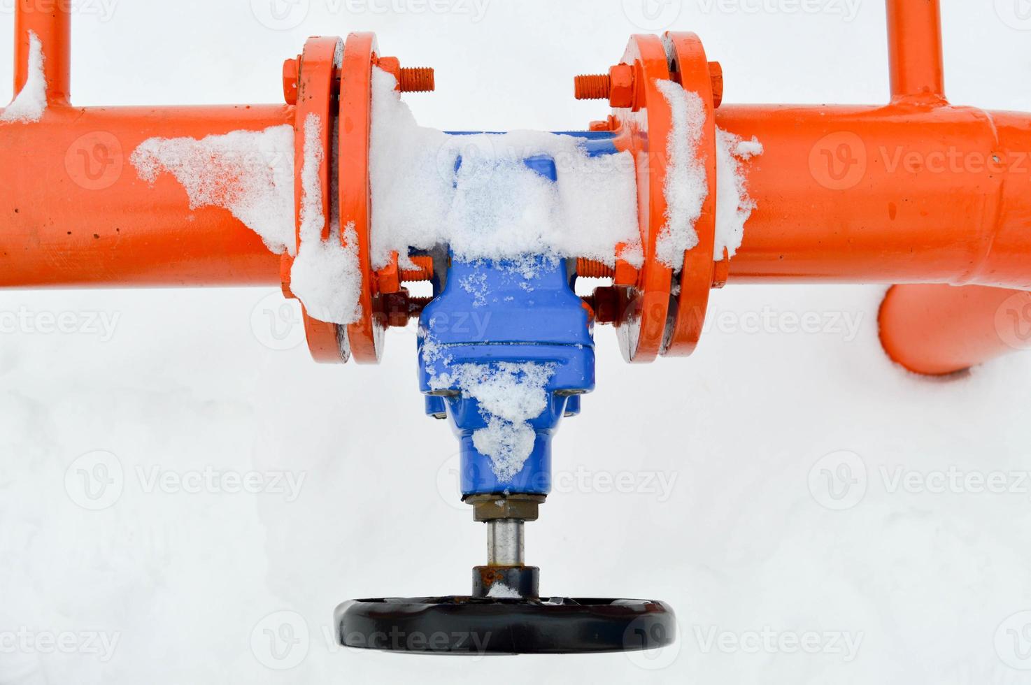 Industrial shut-off regulating protective pipe fittings. Black valve for opening, closing on an iron orange metal pipe with flanges, studs, nuts against the background of white snow in winter photo