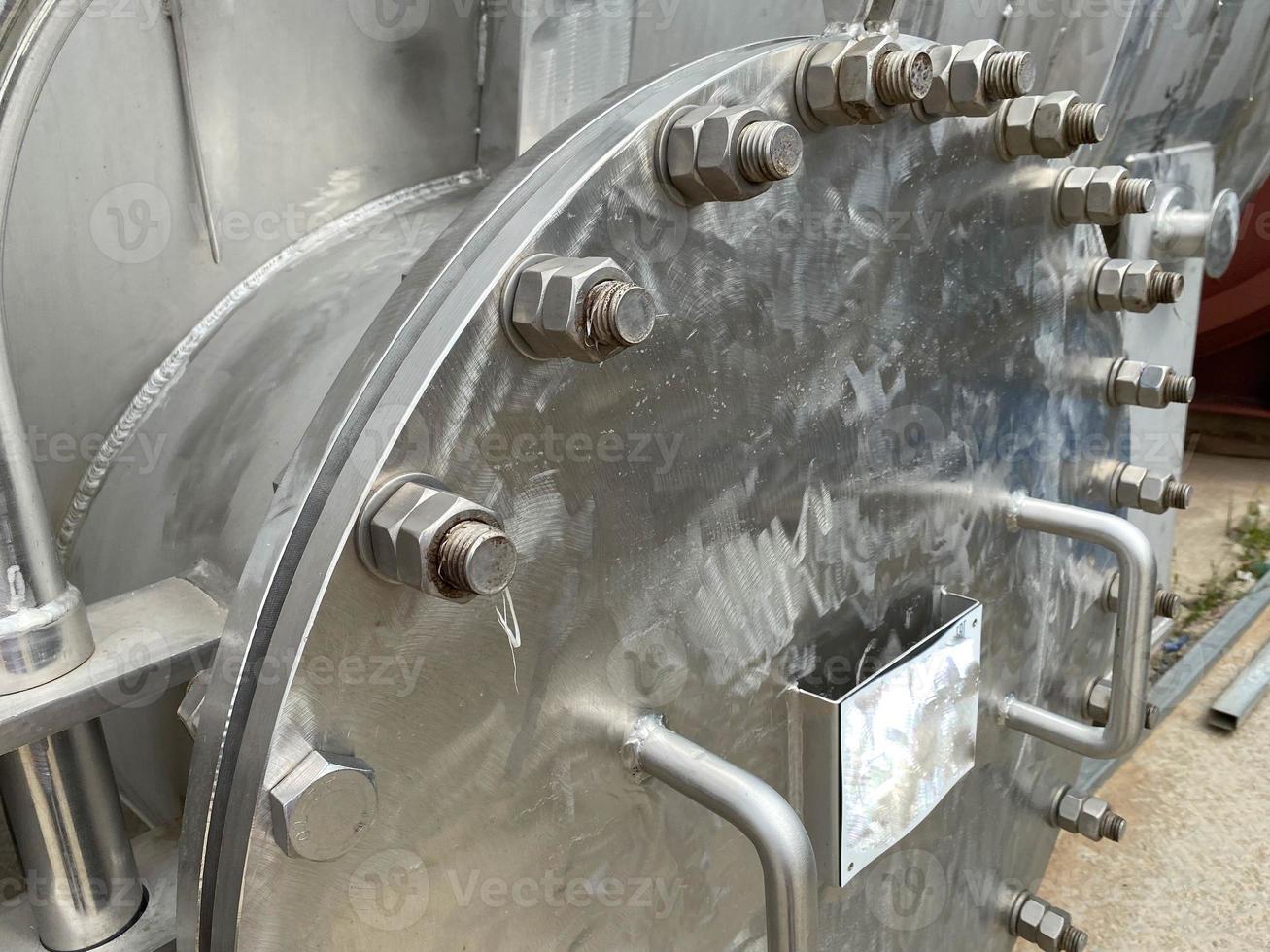 Large shiny iron metal round manhole cover with bolts and nuts for shell and tube heat exchanger or industrial stainless steel column for refinery petrochemical plant equipment photo
