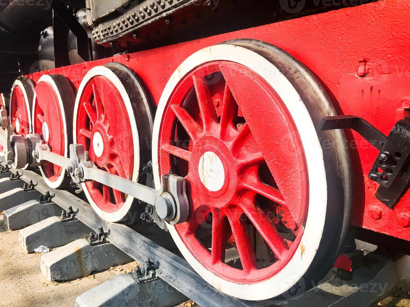 Large iron wheels of a red and black train standing on rails and suspension elements with springs of an old industrial steam locomotive photo