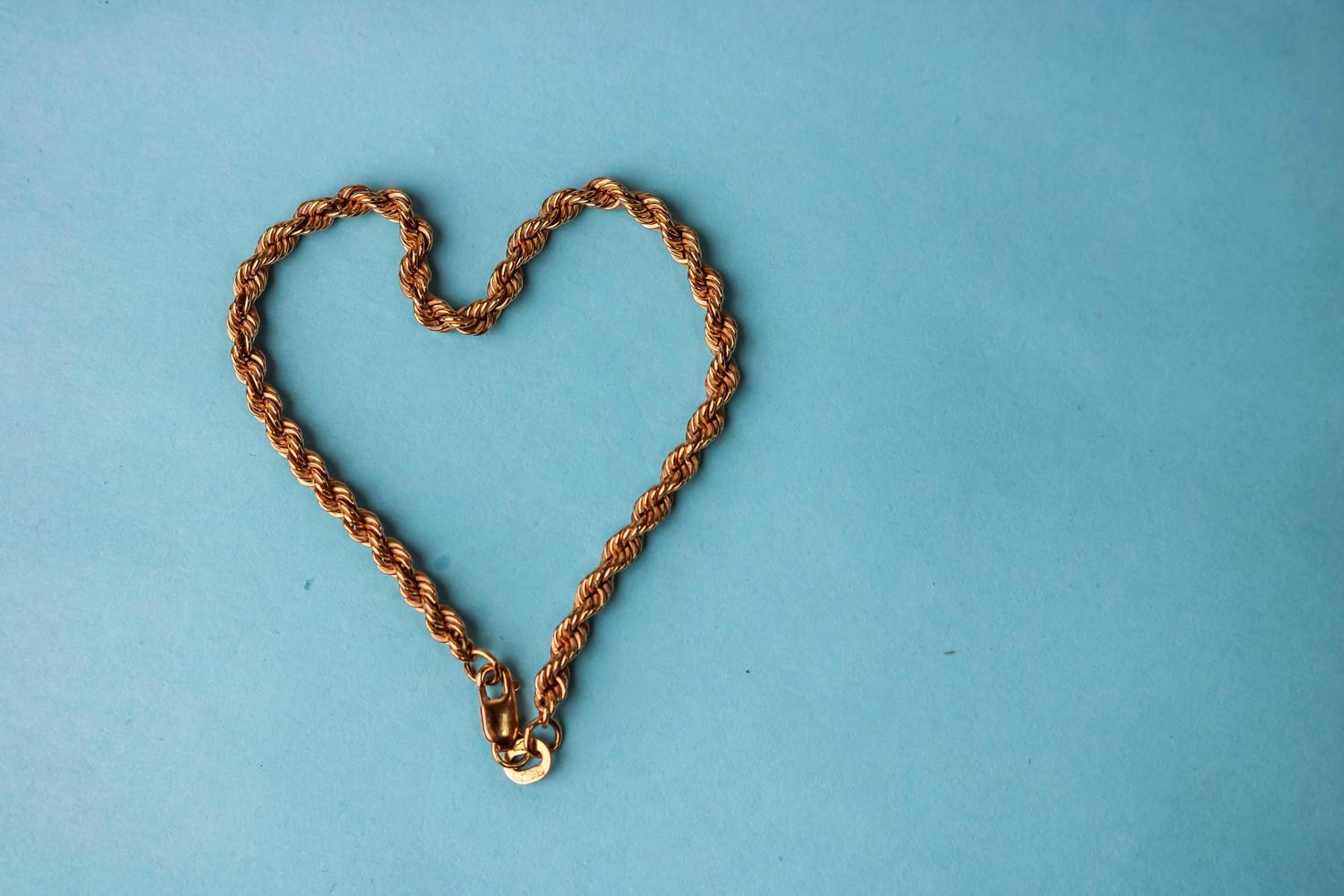 textura de una hermosa cadena dorada querida festiva de tejido único en forma de corazón sobre un fondo azul y espacio de copia. concepto amor, propuesta de matrimonio, matrimonio, st. día de San Valentín foto