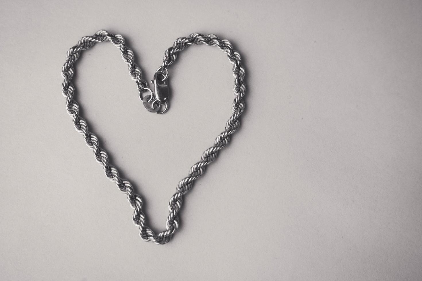 Texture of a beautiful golden festive chain unique weaving in the shape of a heart on a black and white background and copy place. Concept love, marriage proposal, marriage, St. Valentines Day photo