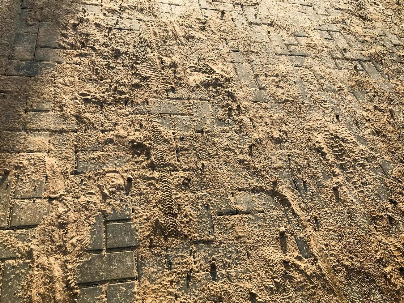 the asphalt is strewn with fine white sand. concrete bricks in mud and stones. road in the sand due to the transport of building material, sand and soil. macro photography photo