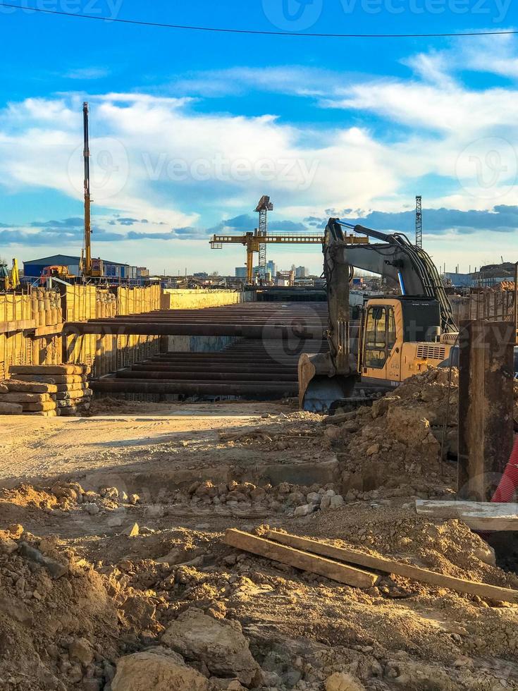 gantry crane to create a metro in the city center. the crane digs earth, sand and stones to build a train line underground. yellow bright crane on a background of blue sky. industrial oil production photo