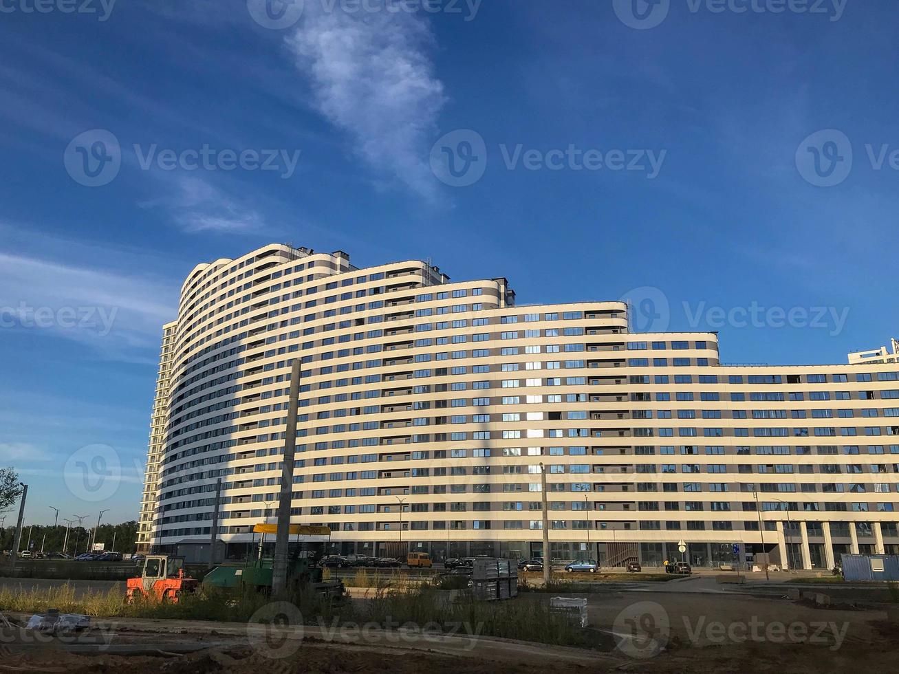 a tall semi-circular white house of an unusual shape. residential building of different heights in the form of a wave. many transparent and clean windows. residential building without balconies photo