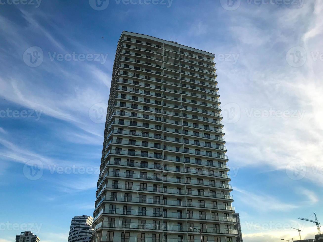 high multi-storey residential building. the building is in Arabic style with terraces. made of blocks, cellular material. panoramic glazing of the building. against the blue sky photo